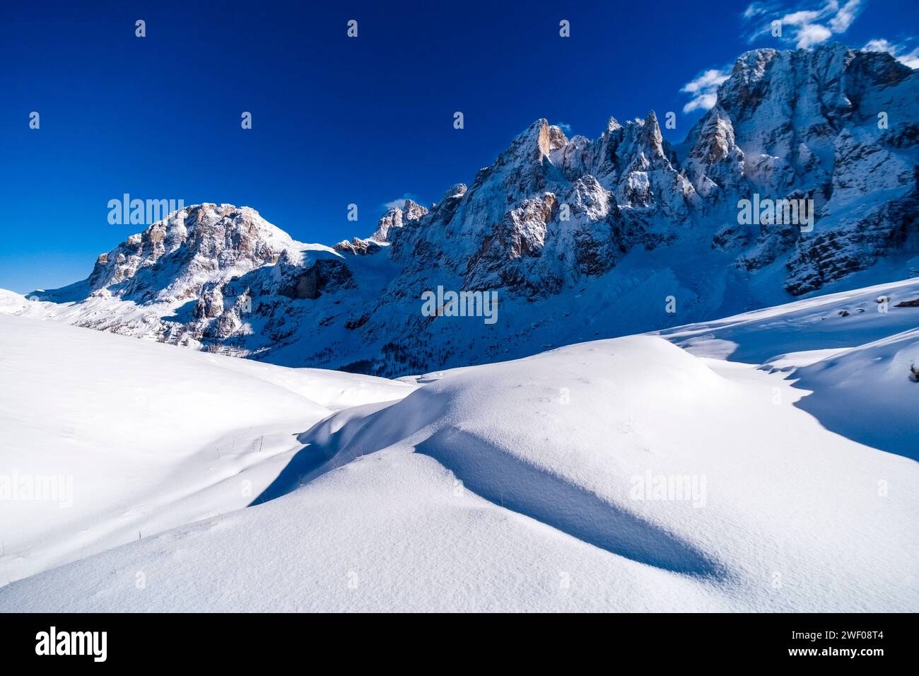 Strutture di neve alla deriva su una collina in Val Venegia sopra il passo Rolle, le cime del gruppo pale in lontananza, in inverno. San Martino di C. Foto Stock