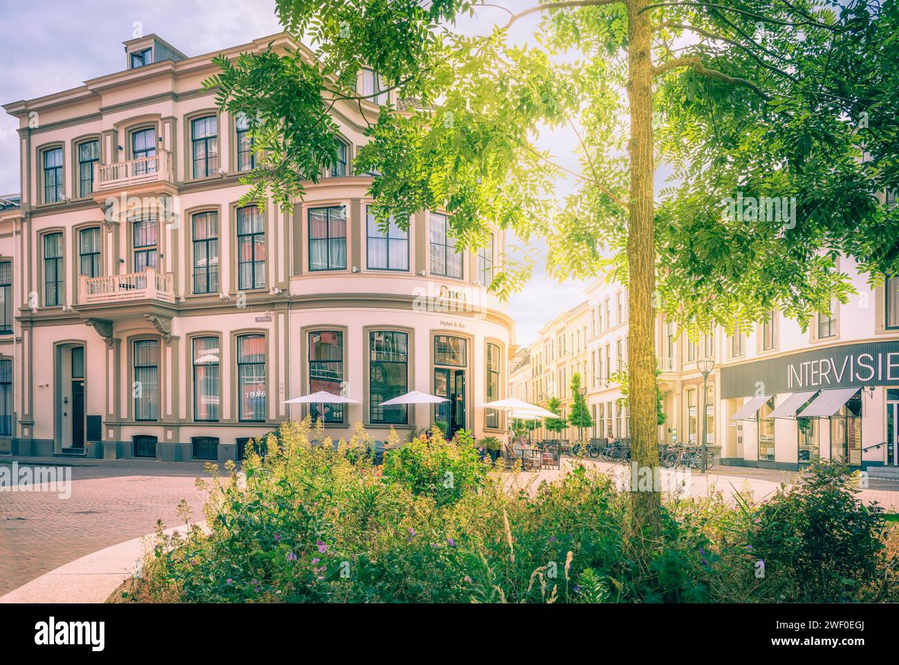 Uno splendido paesaggio urbano caratterizzato da diversi edifici intorno a un cortile aperto, con uno splendido giardino fiorito in primo piano Foto Stock