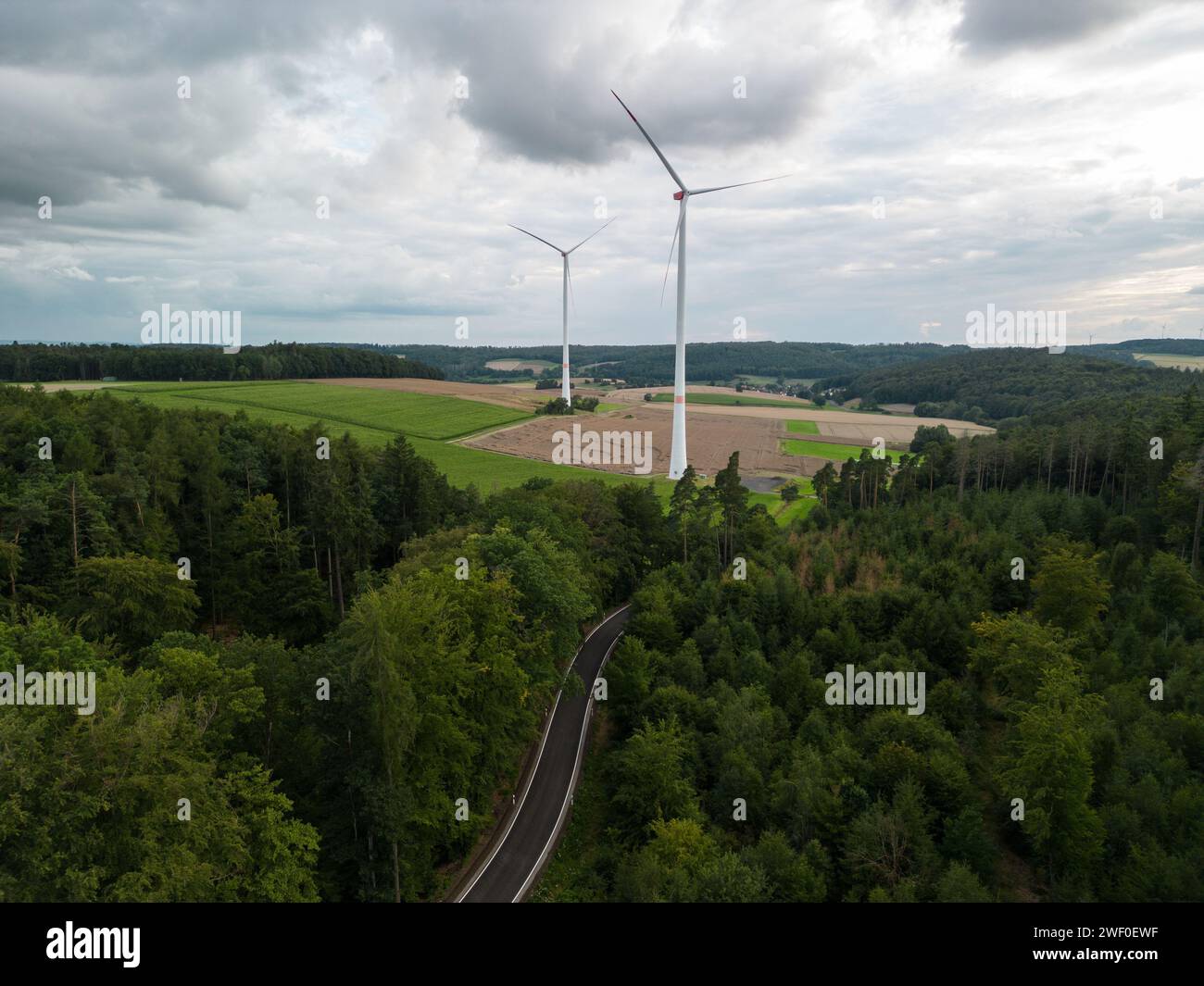 Vista ad alto angolo delle turbine eoliche tra i campi sotto il cielo nuvoloso in germania Foto Stock