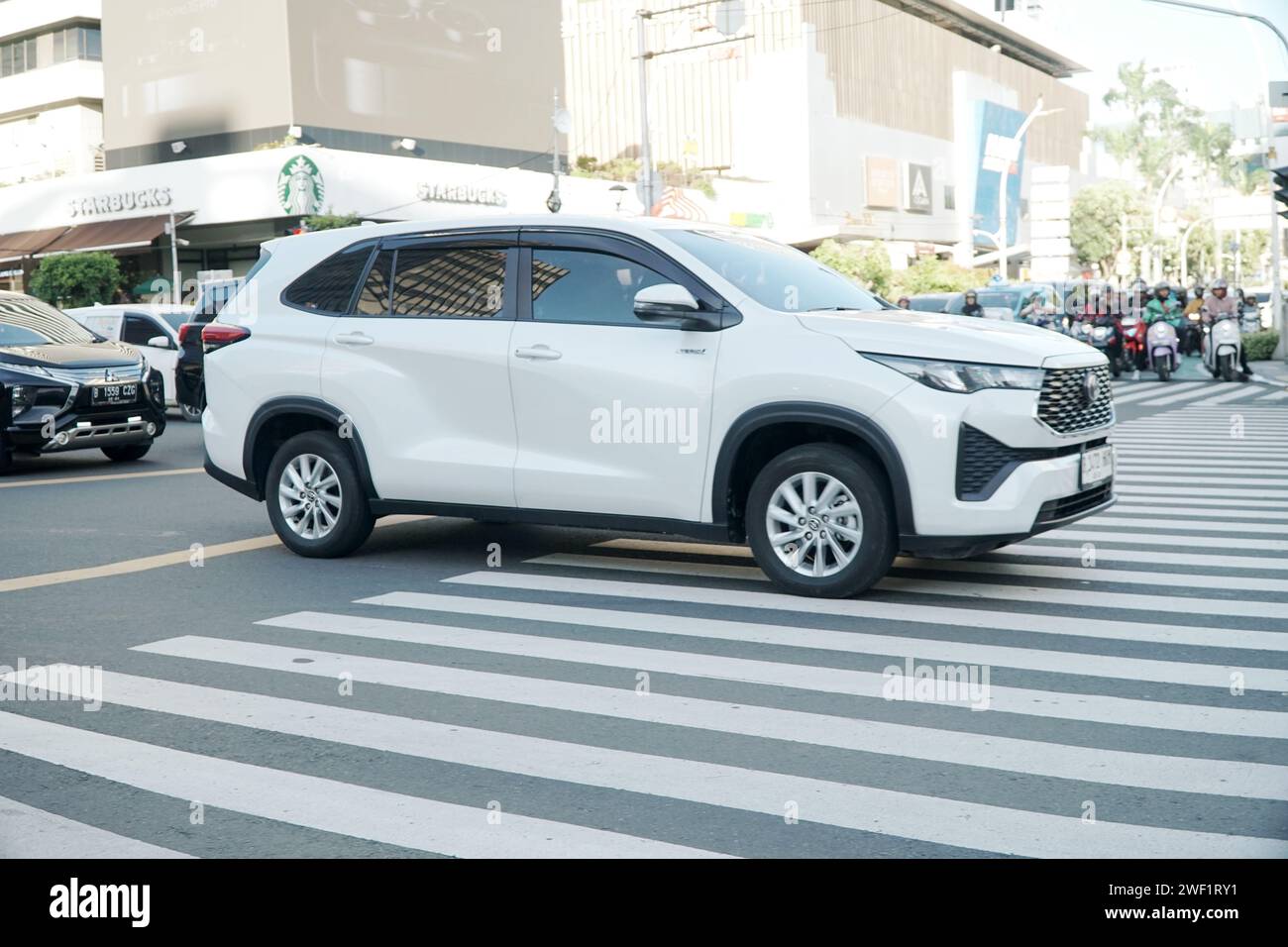 Auto ibrida Toyota Kijang Innova Zenix bianca, che guida nella principale area commerciale e finanziaria, MH Thamrin Street, Giacarta, Indonesia. Foto Stock
