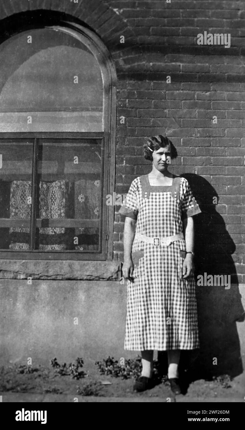 Una donna e' fermamente posta contro un muro di mattoni, ca. 1920. Foto Stock