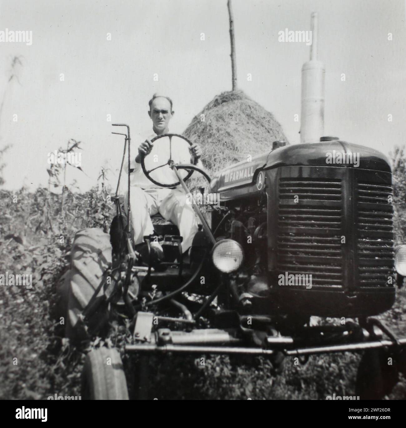 Un uomo siede in cima al suo trattore Farmall, CA. 1950. Foto Stock