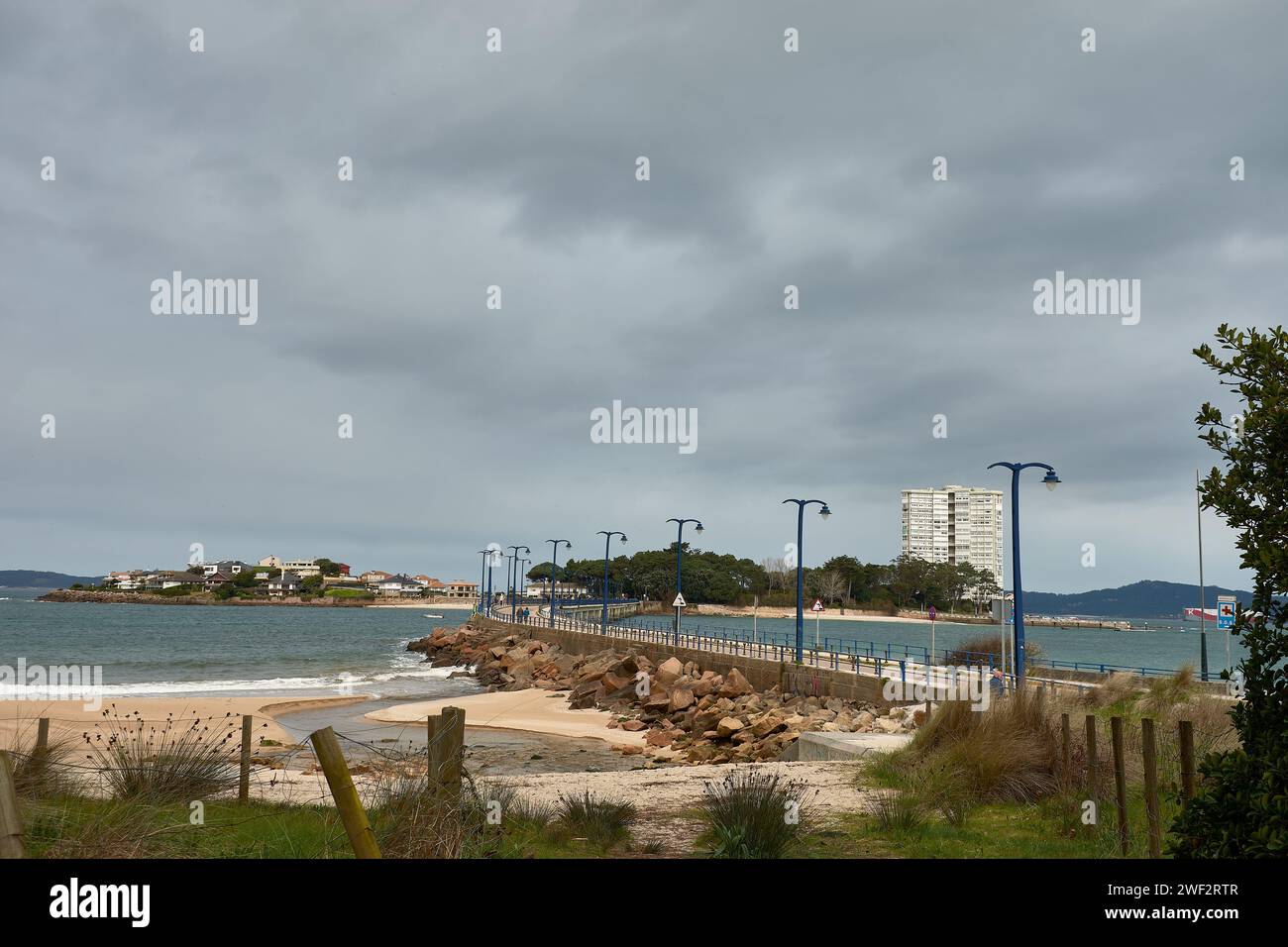 L'isola di Toralla con il suo enorme edificio, il suo ponte sotto un cielo nuvoloso a Vigo, Galizia, Spagna Foto Stock