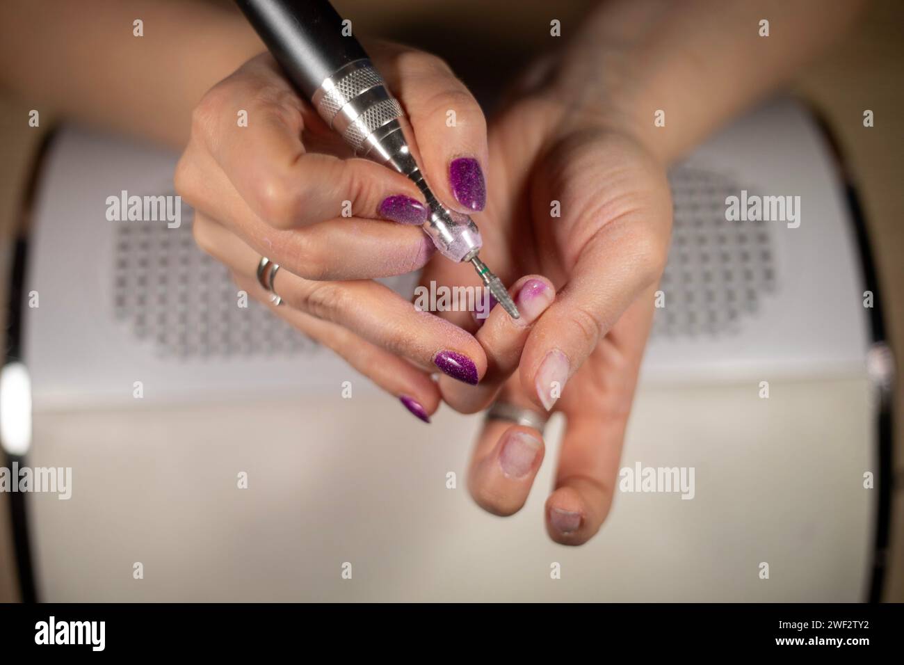 Primo piano di una donna irriconoscibile che rimuove lo smalto con la lima, primo piano di una cuticola femminile irriconoscibile intorno all'unghia Foto Stock