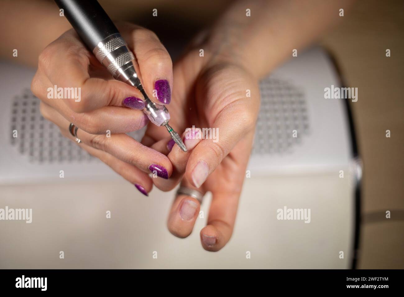 Primo piano di una donna irriconoscibile che rimuove lo smalto con la lima, primo piano di una cuticola femminile irriconoscibile intorno all'unghia Foto Stock