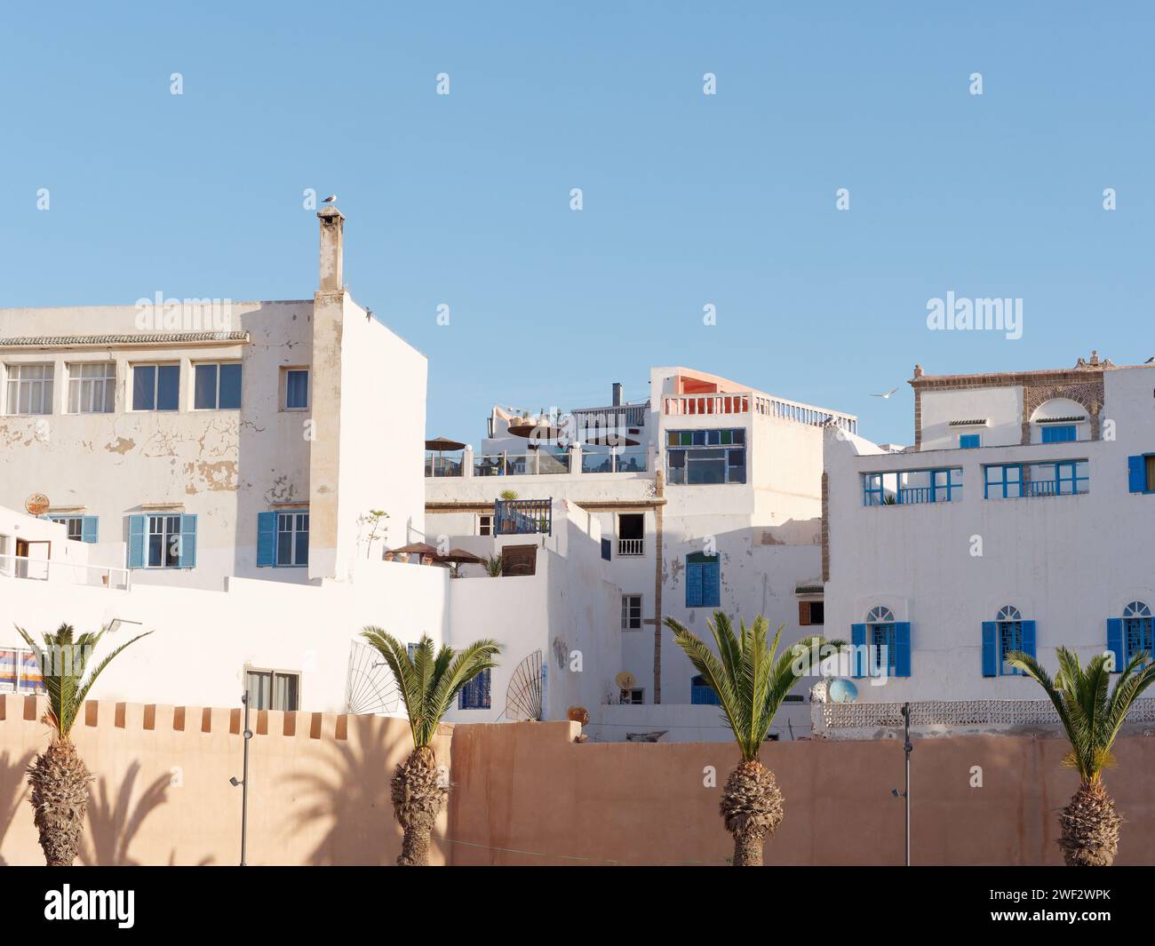 Edifici bianchi con terrazze sul tetto accanto alle mura della città nella storica Medina di Essaouira, Marocco, 28 gennaio 2024 Foto Stock
