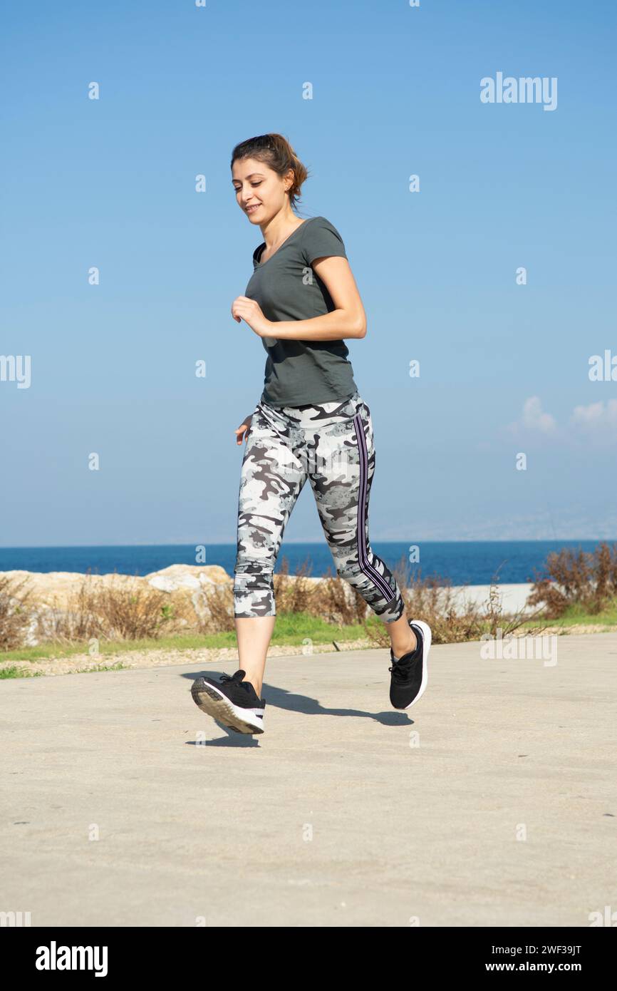 Donna in corsa sulla spiaggia Foto Stock