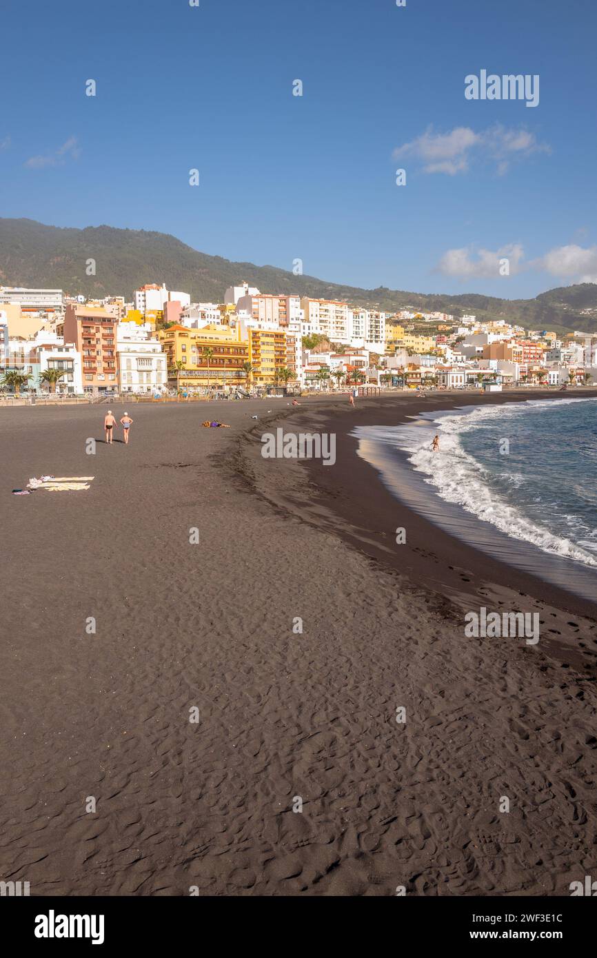 Bagnanti di sole godendosi il sole invernale e il calore sulle sabbie nere dell'isola delle canarie di Santa Cruz, la Palma, Spagna. Foto Stock