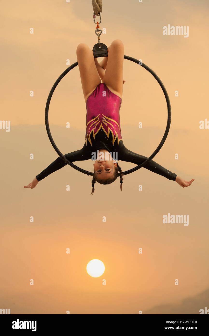 ginnasta di 12 anni che si esibisce all'aria aperta su un canestro aereo Foto Stock