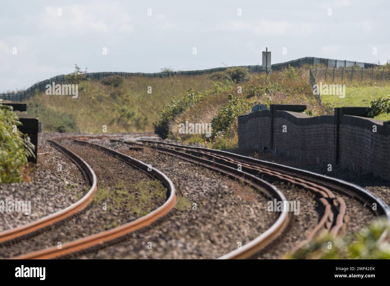 Una vista teleobiettivo della linea ferroviaria della Durham Coast che attraversa il viadotto di Hawthorn, esagerando le curve dei binari e la muratura Foto Stock