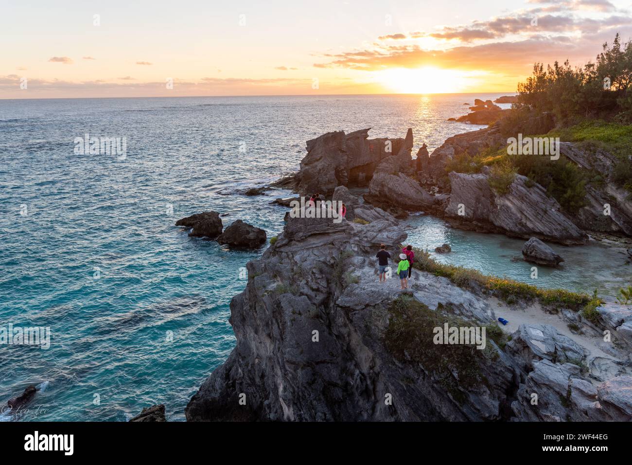 Catturando la bellezza serena della costa delle Bermuda al tramonto, dove la grande roccia si erge come una maestosa silhouette sullo sfondo tranquillo dell'oceano Foto Stock