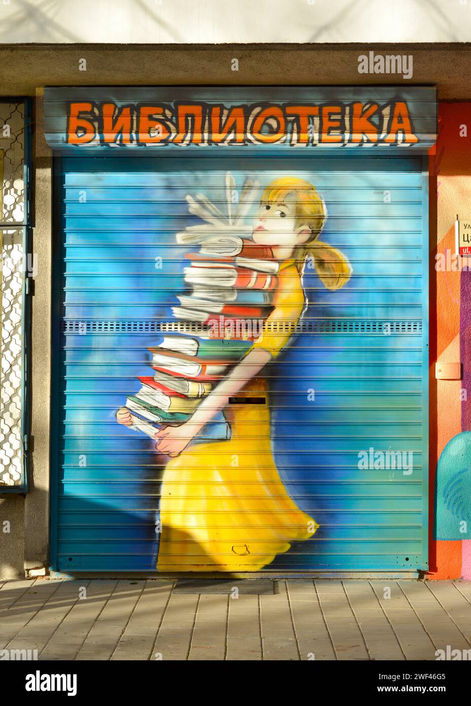 Ragazza che porta con sé una grande pila di libri in mano graffiti su una piccola porta chiusa della biblioteca del quartiere locale a Sofia, Bulgaria, Europa orientale, Balcani Foto Stock