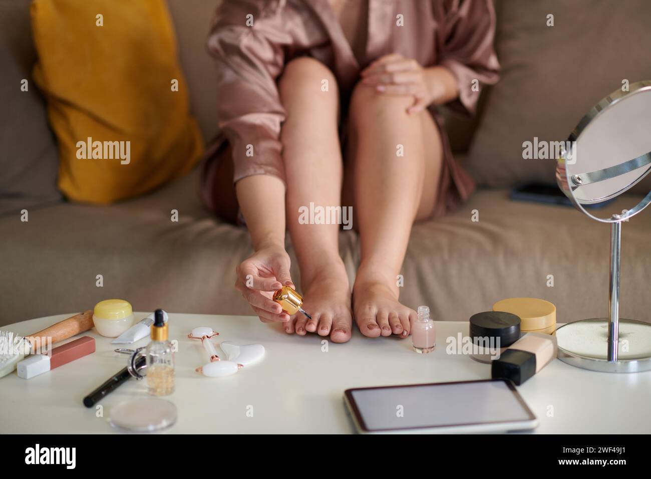 Donna che applica lo smalto per unghie quando fa pedicure a casa Foto Stock