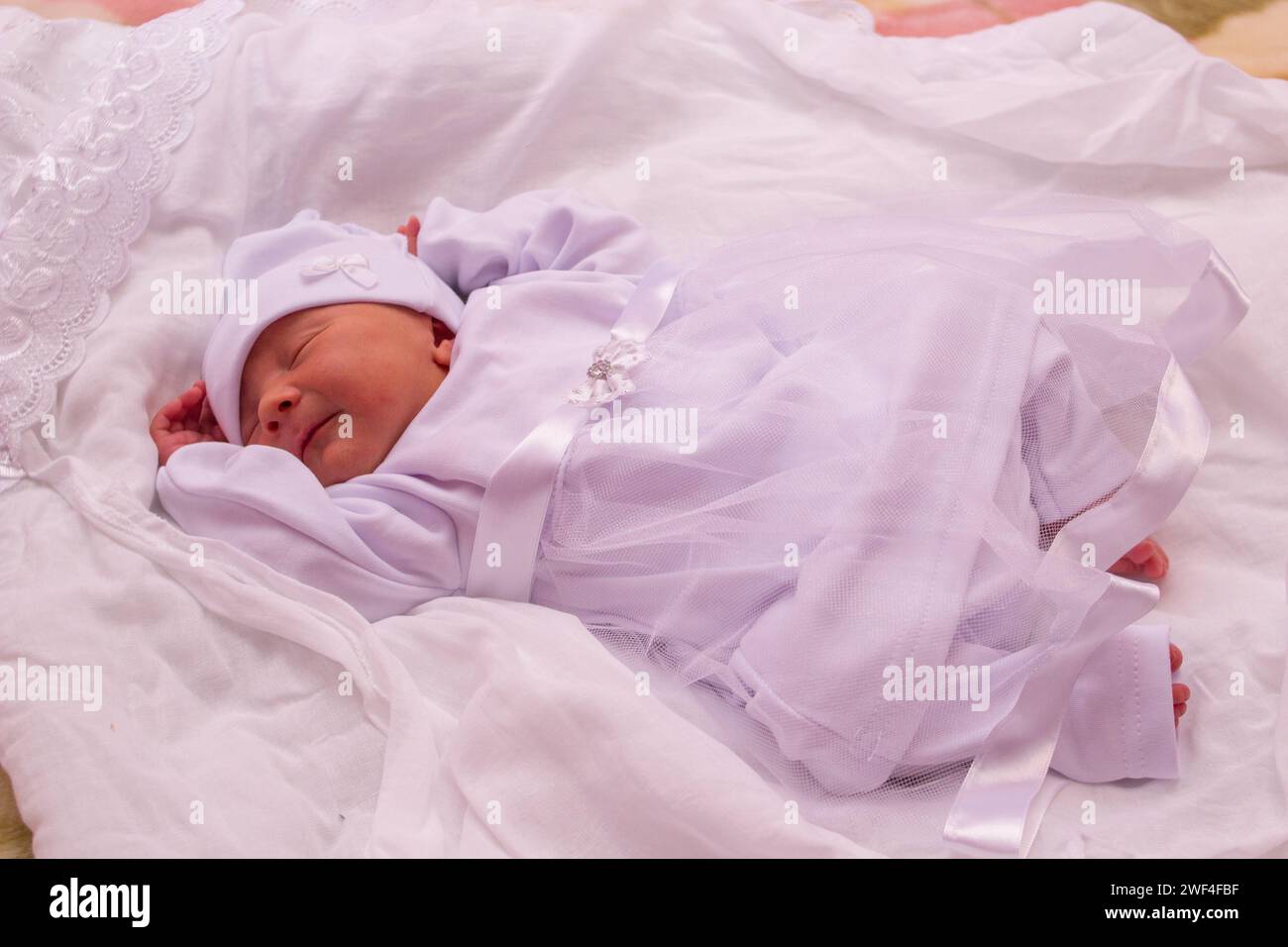 bel bambino che dorme su una coperta bianca in un vestito Foto Stock