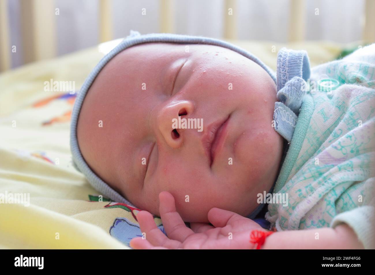 Il bambino dorme a braccia aperte e senza succhietto nella base Foto Stock