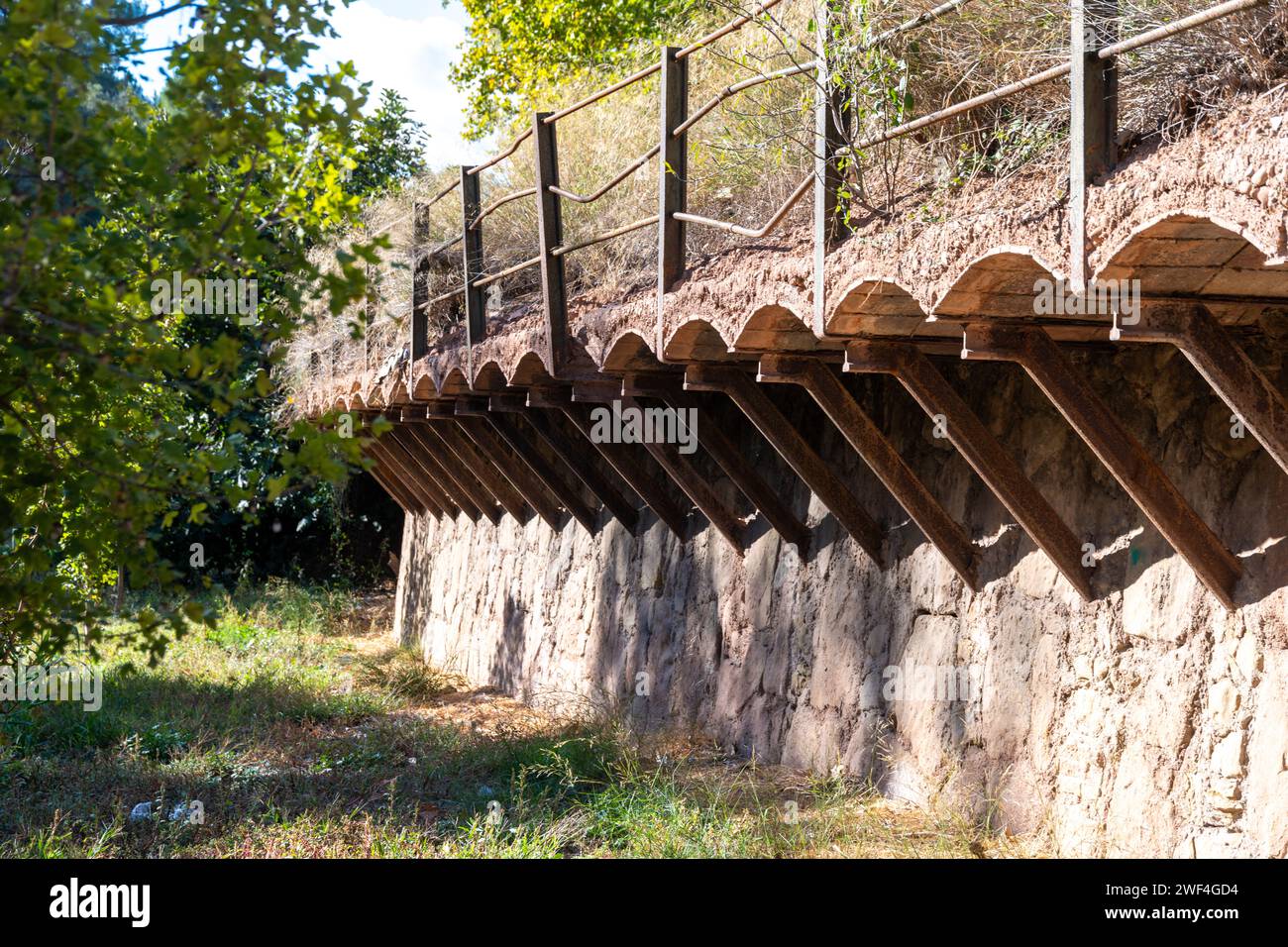 Un sentiero sopraelevato per attraversare un fiume e un prato a piedi asciutti. Il sentiero è ampliato con supporti in legno e il ponte è realizzato in grande pietra b Foto Stock