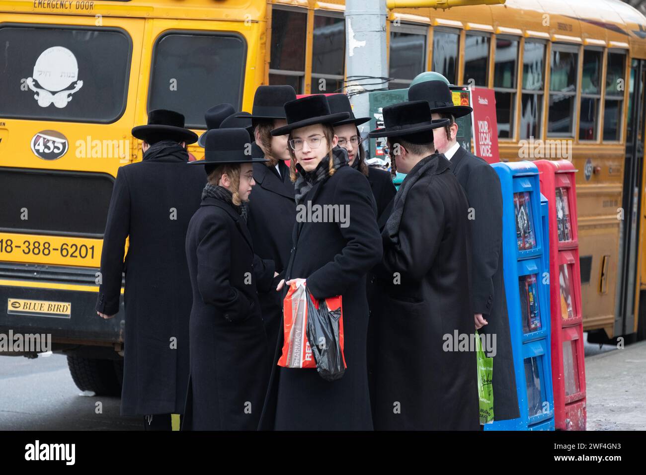 Un gruppo di studenti ebrei ortodossi aspetta un autobus per trasportarli in una classe di Talmud dall'altra parte di Brooklyn, New York. Foto Stock