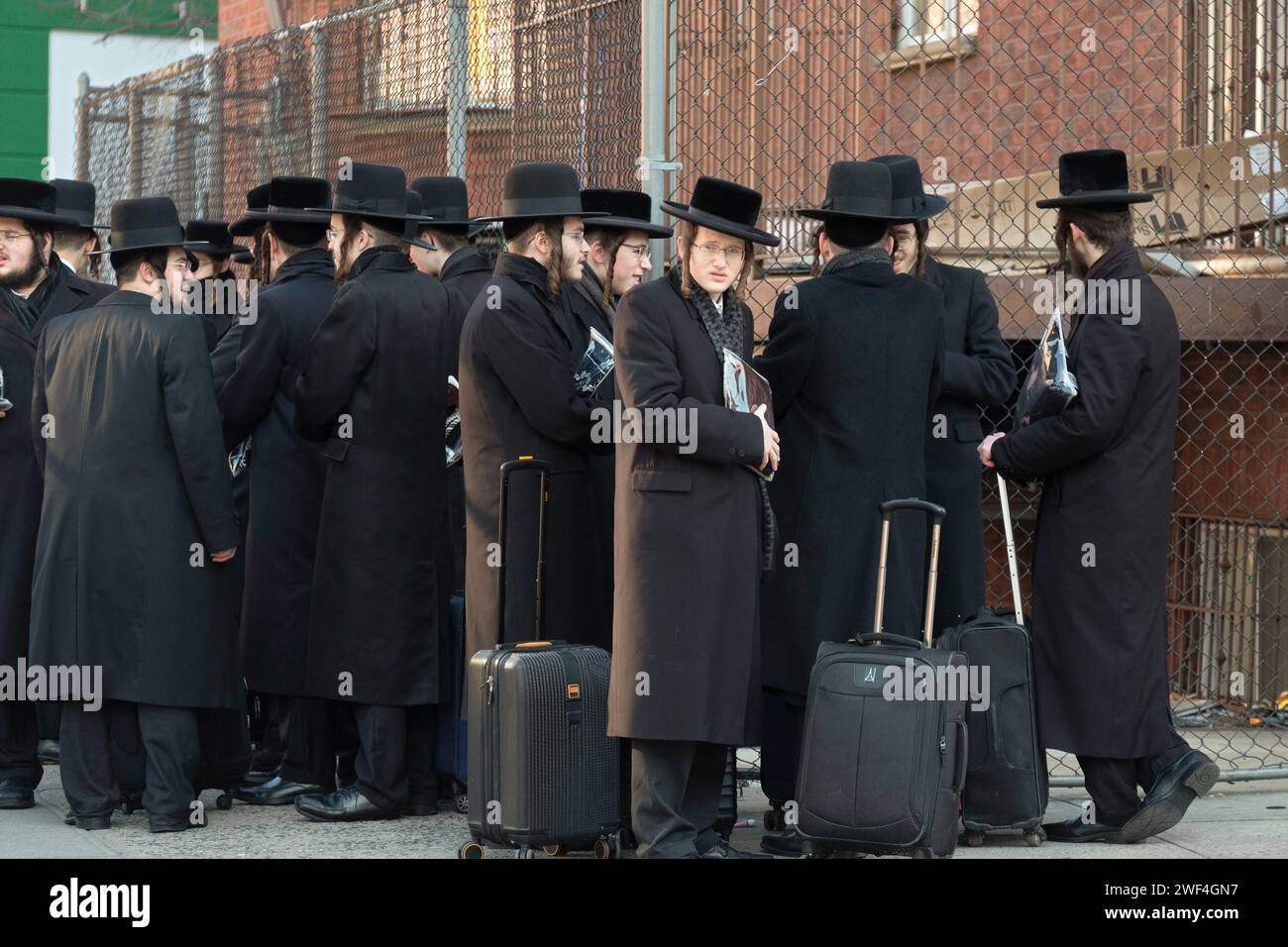 Un gruppo di giovani ebrei ortodossi molto affollati aspetta un autobus per trasportarli alle lezioni dall'altra parte di Brooklyn. A Williamsburg. Foto Stock