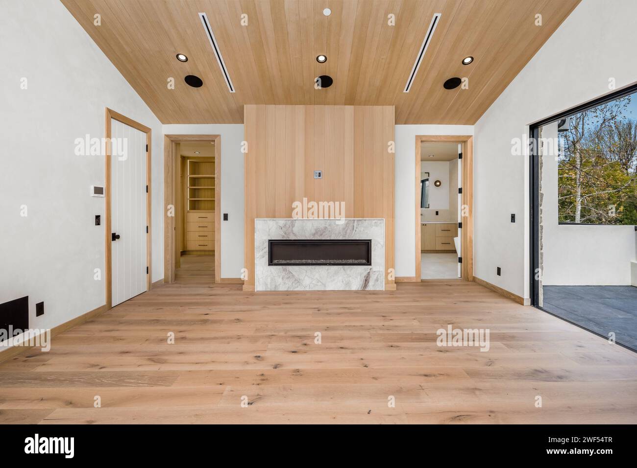 Accogliente soggiorno con caminetto, soffitto alto e pavimento in legno Foto Stock