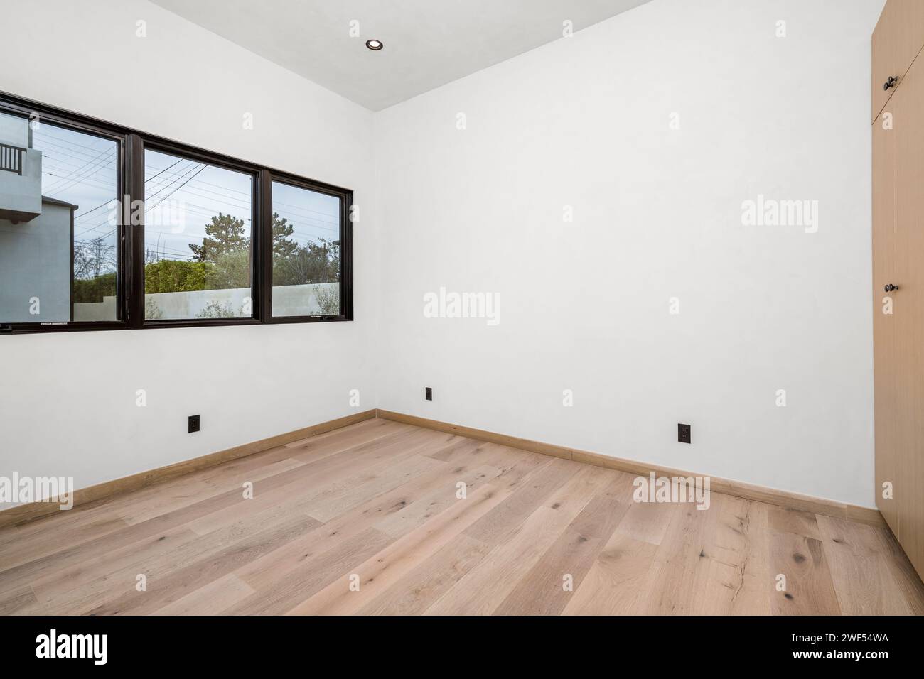 Camera bianca vuota con pavimenti in legno e finestra Foto Stock