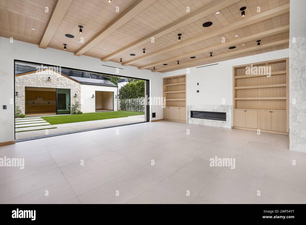 Camera spaziosa con travi in legno, pareti bianche luminose e soffitto Foto Stock