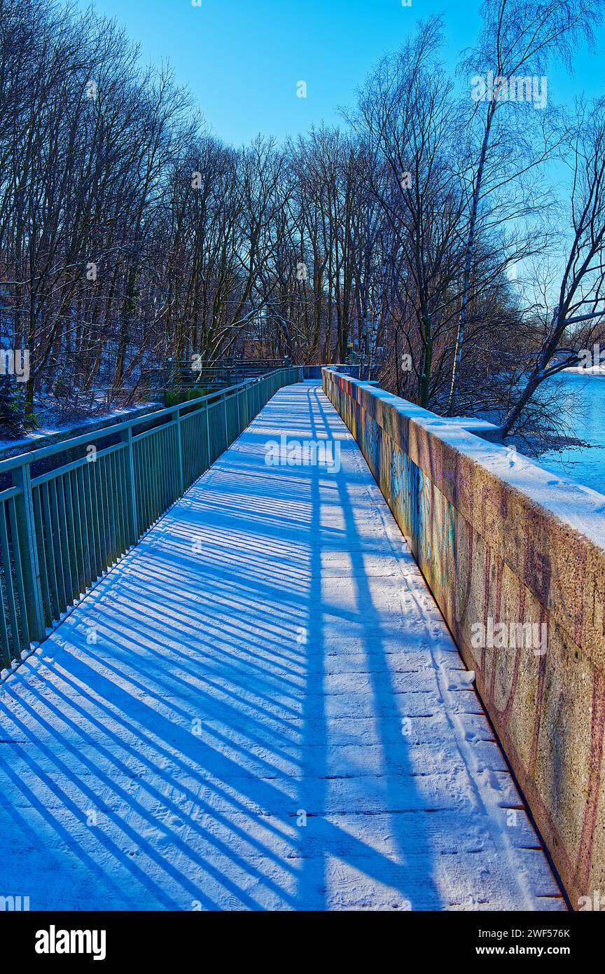 Ponte pedonale coperto da neve, luci e ombre sotto il cielo blu Foto Stock