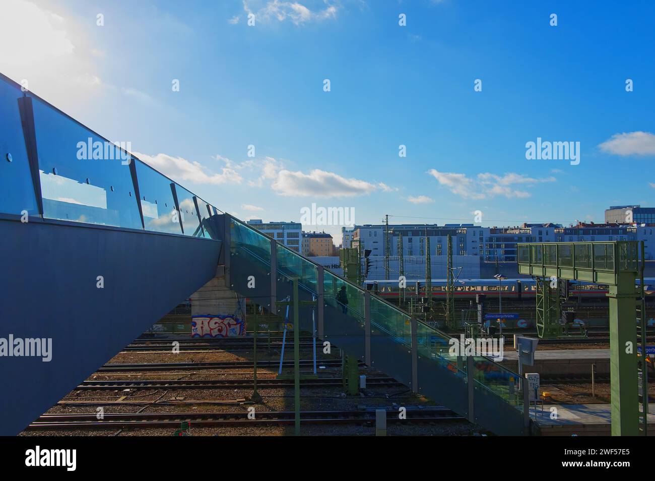 Ponte pedonale e vista parziale di una stazione ferroviaria sotto il cielo blu Foto Stock