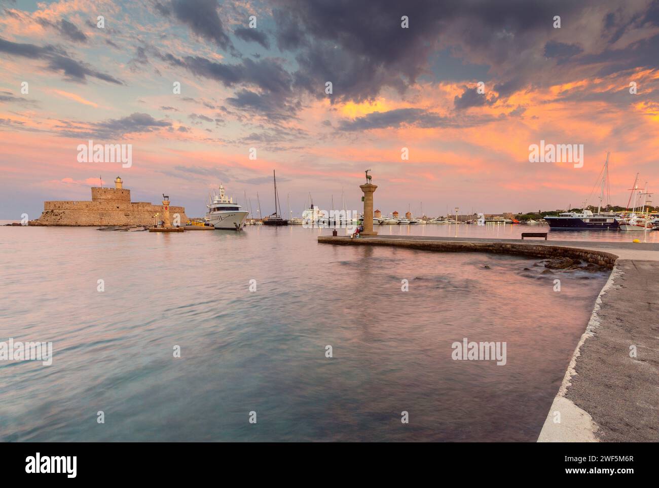 Vista panoramica del vecchio faro e del porto di Mandraki al tramonto. Rhodes. Grecia. Foto Stock
