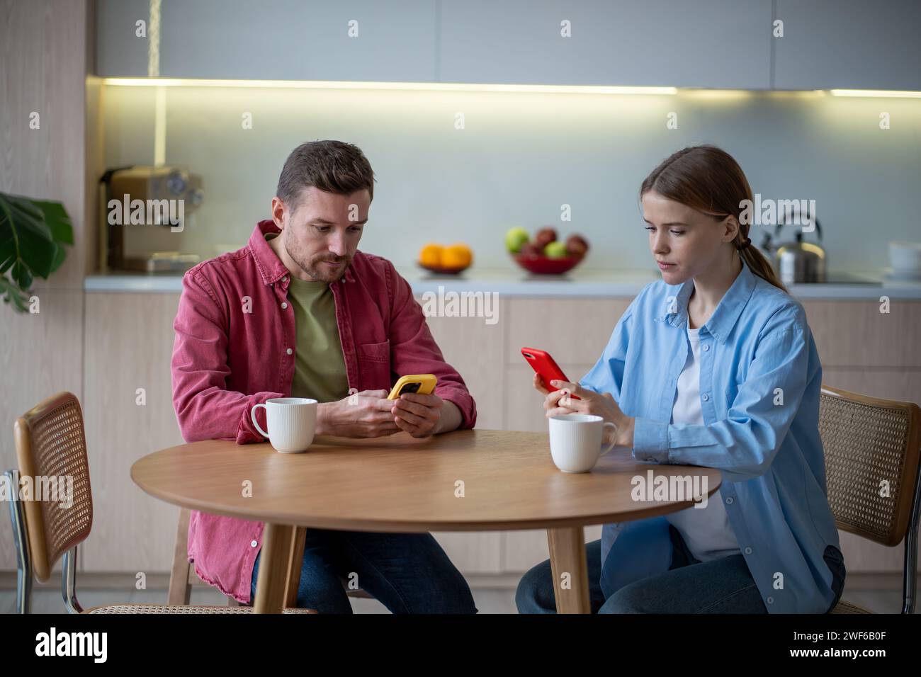 Una coppia premurosa dipendente dai gadget mobili che navigano in Internet in silenzio ignorandosi a vicenda Foto Stock