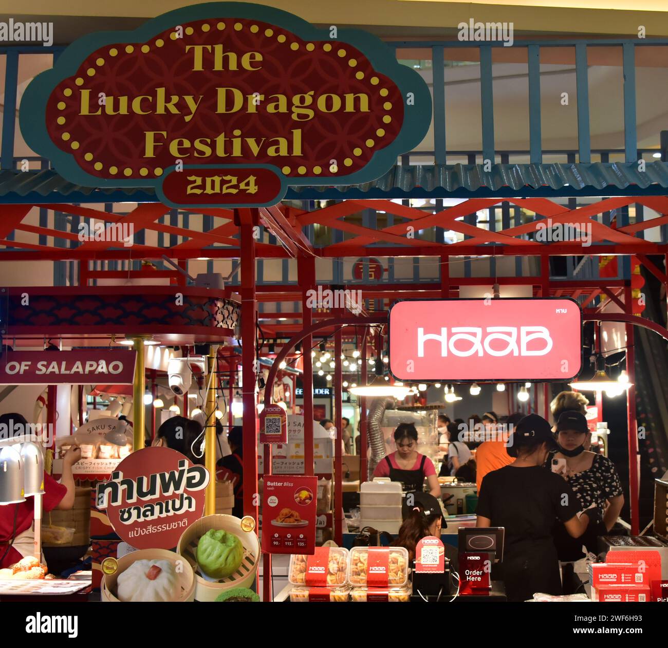 Cartello del festival del drago fortunato presso il centro commerciale Silom Complex, Bangkok, Thailandia, Sud Est Asiatico. Nella cultura cinese il 2024 è l'anno del drago di legno. Il capodanno cinese 2024 scenderà sabato 10 febbraio 2024, iniziando un anno del Drago di legno. Clienti al food mart del centro commerciale. Foto Stock