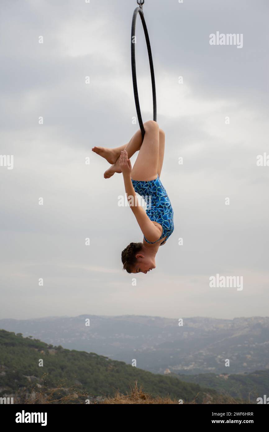 Piccola ginnasta femminile che si esibisce all'aperto su un canestro aereo Foto Stock