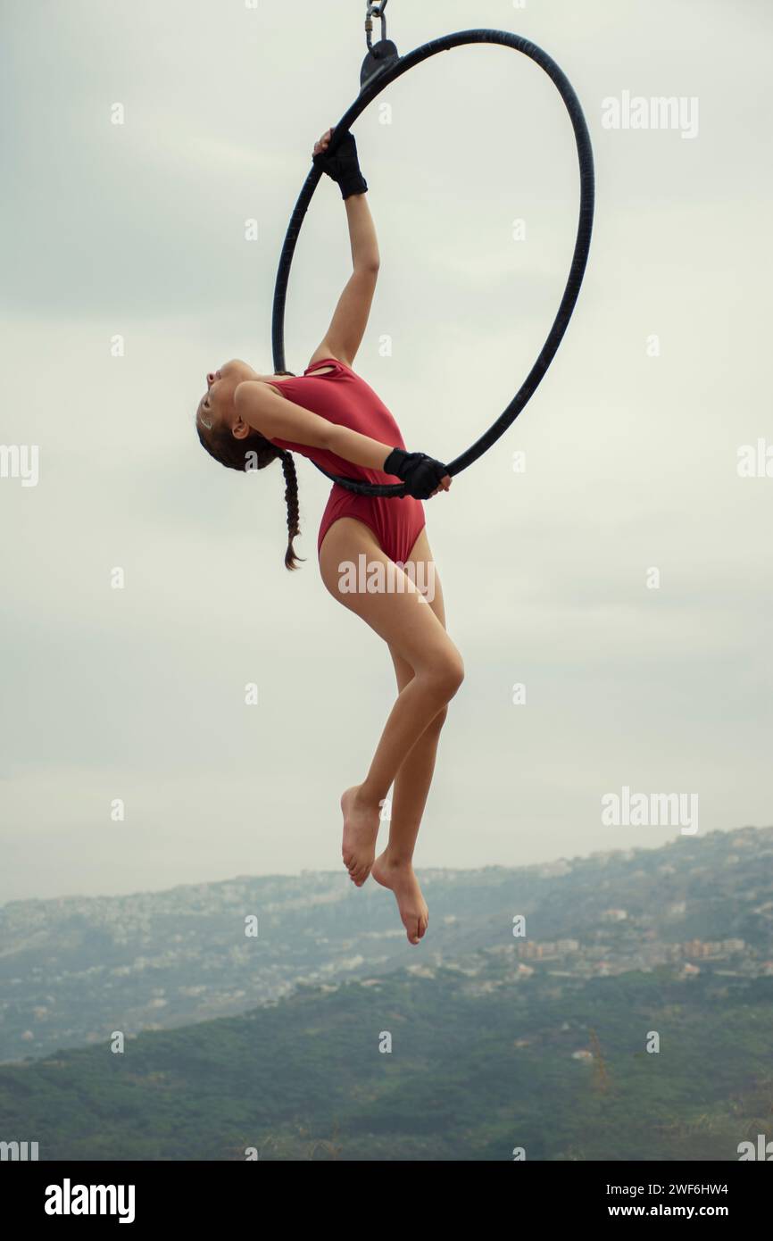 Piccola ginnasta femminile che si esibisce all'aperto su un canestro aereo Foto Stock