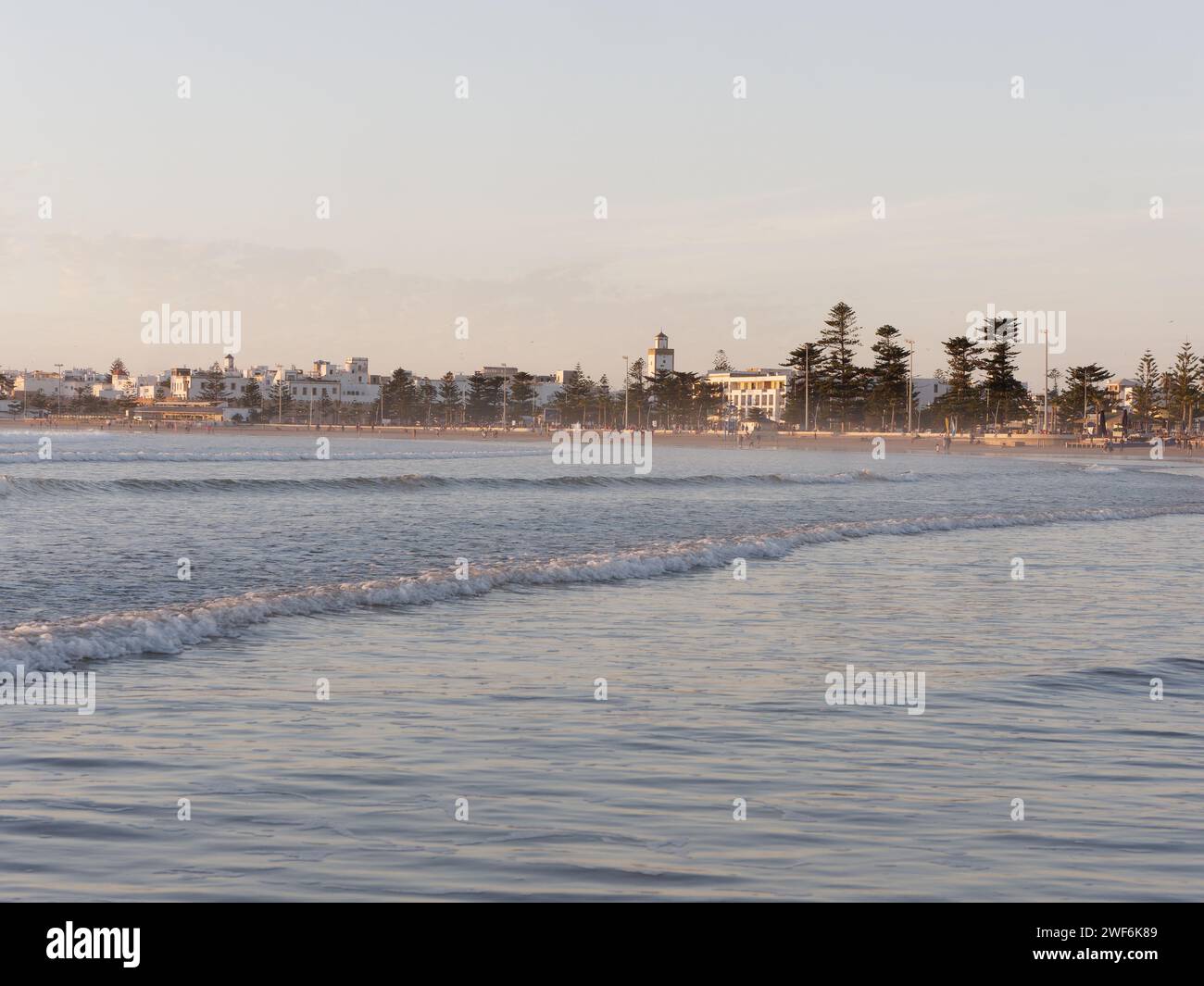 Onde dolci rollin con la storica Medina alle spalle al tramonto a Essaouira, Marocco, 28 gennaio 2024 Foto Stock