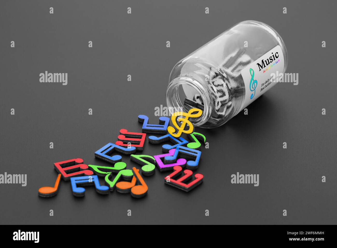 Note musicali multicolore fuoriescono da un vaso di vetro. Il concetto di trattamento con la musica. Foto Stock