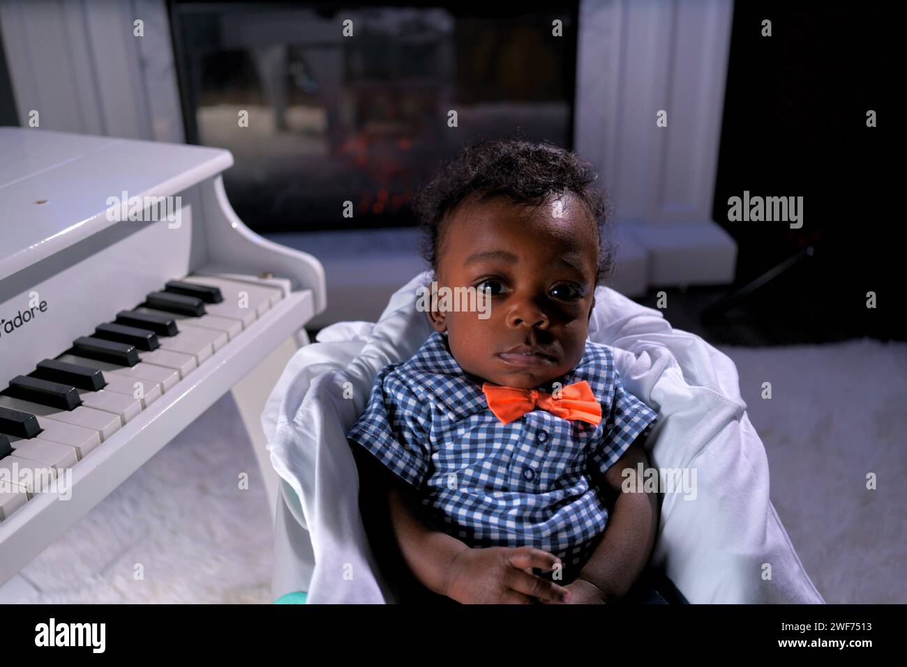 Un giovane bambino afroamericano seduto accanto a un pianoforte a coda Foto Stock
