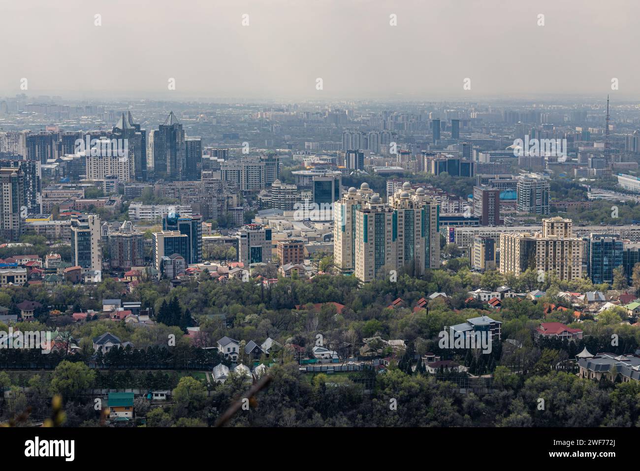 Vista panoramica su Almaty dal parco del monte Kok Tobe. Paesaggio urbano durante il giorno primaverile. Haze smog sopra la città, problema ecologico. Repubblica del Kazakistan, Asi centrale Foto Stock