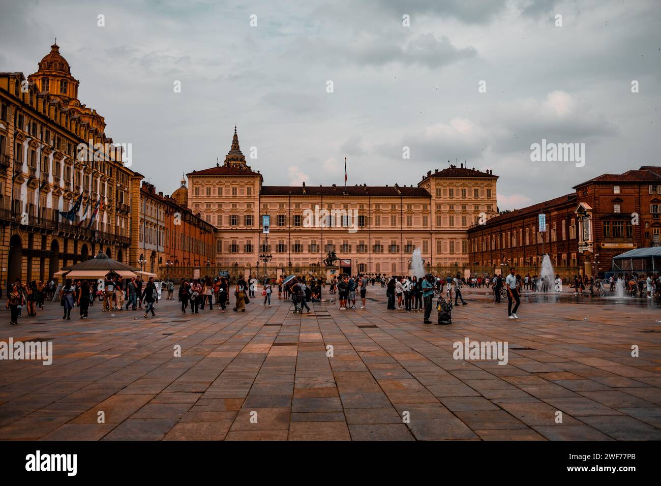 I visitatori e gli abitanti del luogo si riuniscono in Piazza Castello, con il grande Palazzo reale di Torino che si erge maestosamente sullo sfondo. Foto Stock