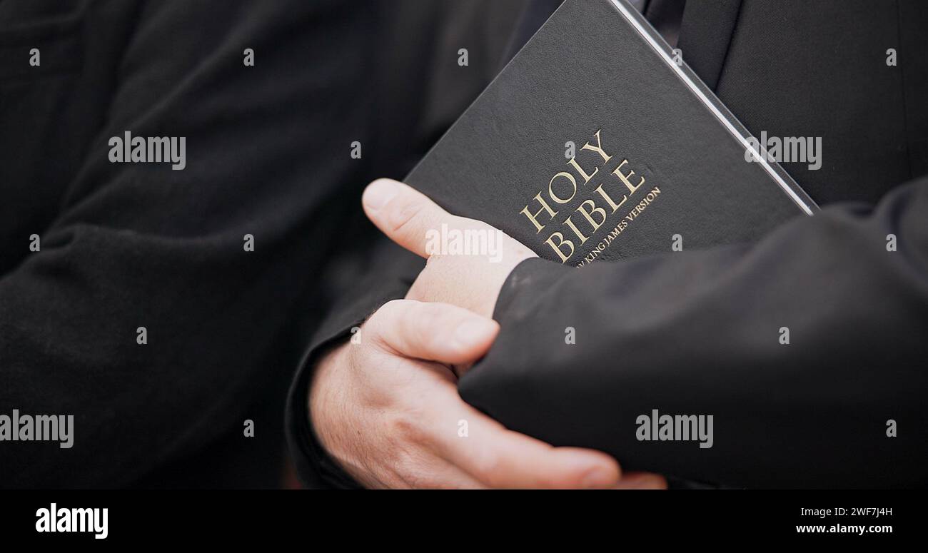 Bibbia, funerale e primo piano delle mani di un prete per religione, triste e lutto in chiesa. Fede, uomo e passaggio spirituale con culto e.. Foto Stock