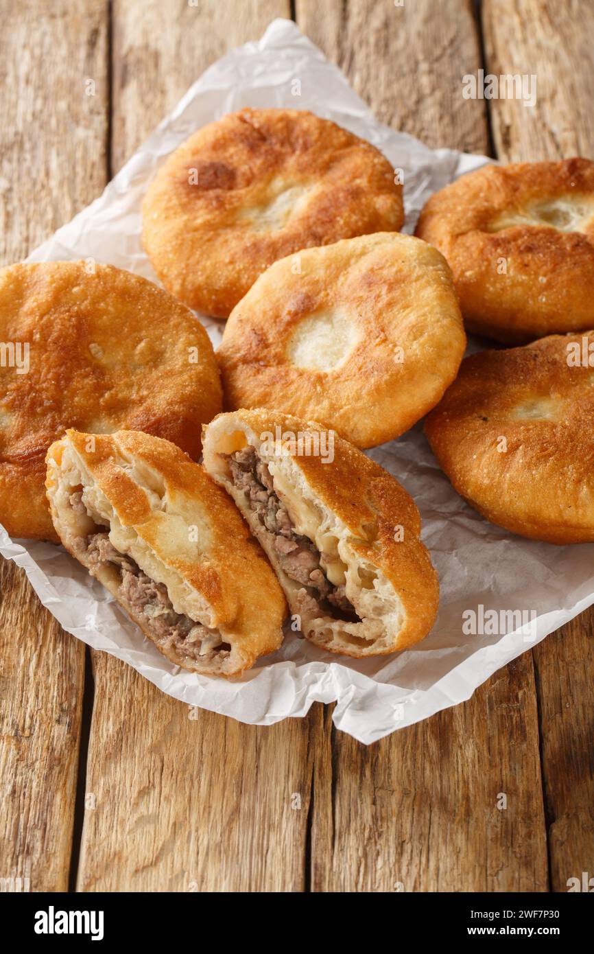 Peremech o belyash è un impasto fritto con primi piani di carne sulla carta su tavola di legno. Verticale Foto Stock