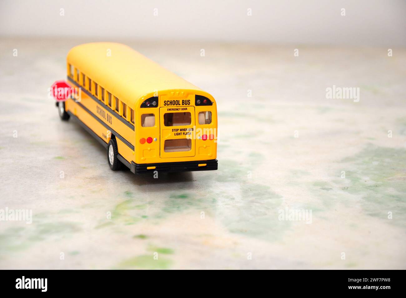 Scuolabus americano in miniatura di colore giallo standard con segnale di stop sul lato. Vista posteriore con messa a fuoco selettiva Foto Stock