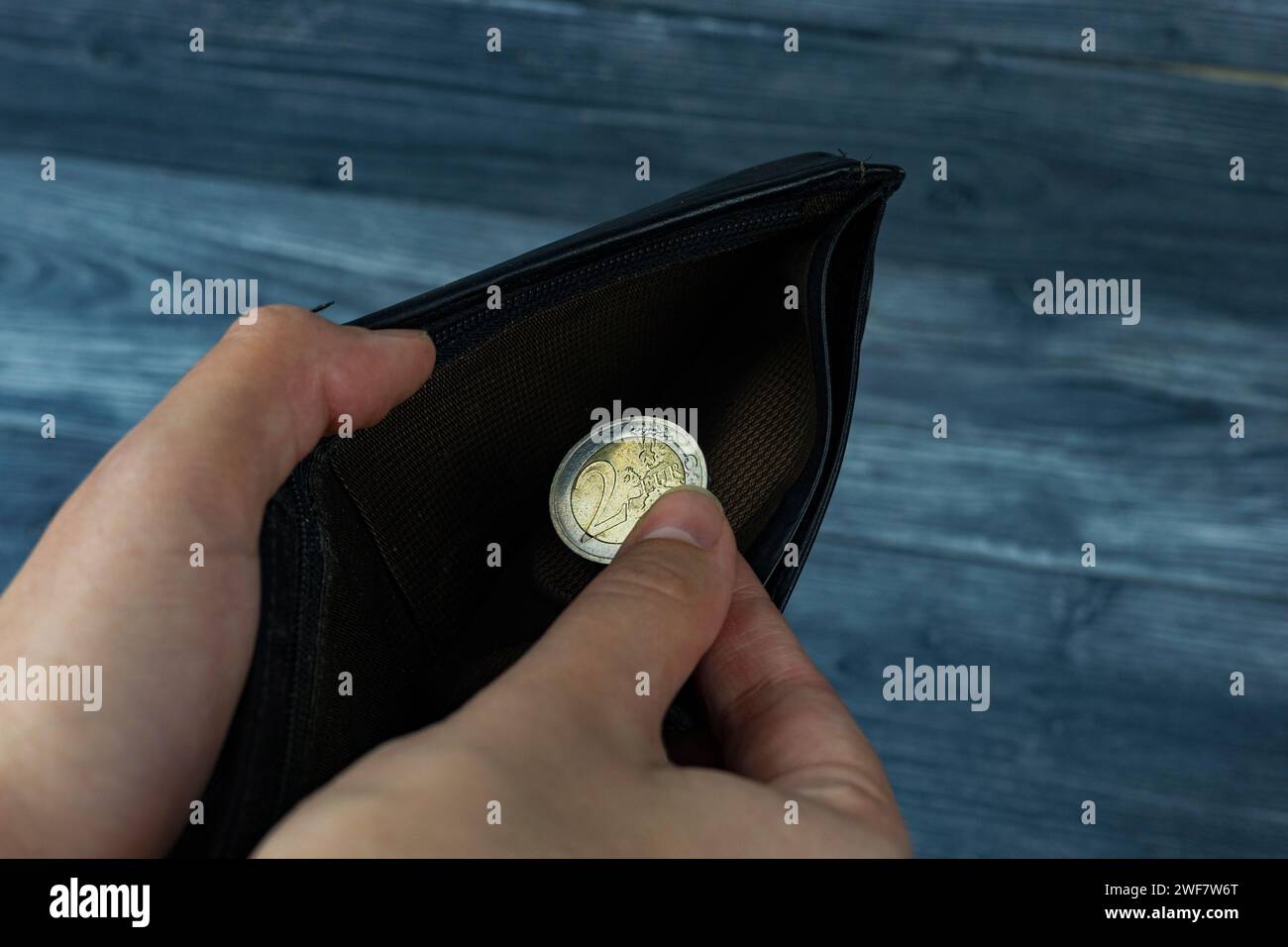 Un portafoglio con denaro e monete in mano su sfondo scuro, vista dall'alto. Una moneta in euro nel palmo della tua mano. Vista in prima persona. Foto Stock