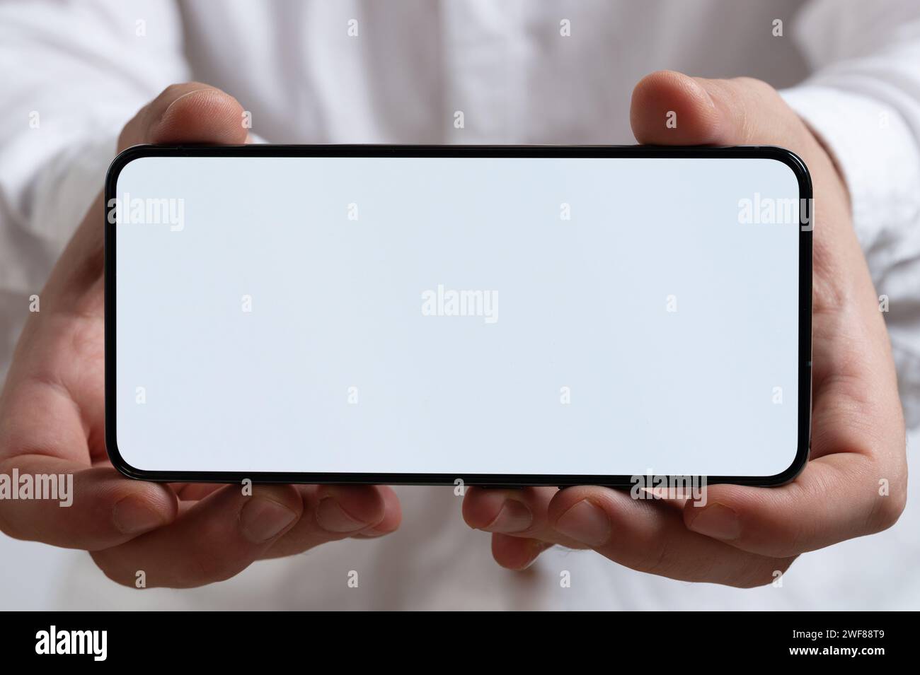 Smartphone con schermo vuoto in vista ravvicinata macro a due mani Foto Stock
