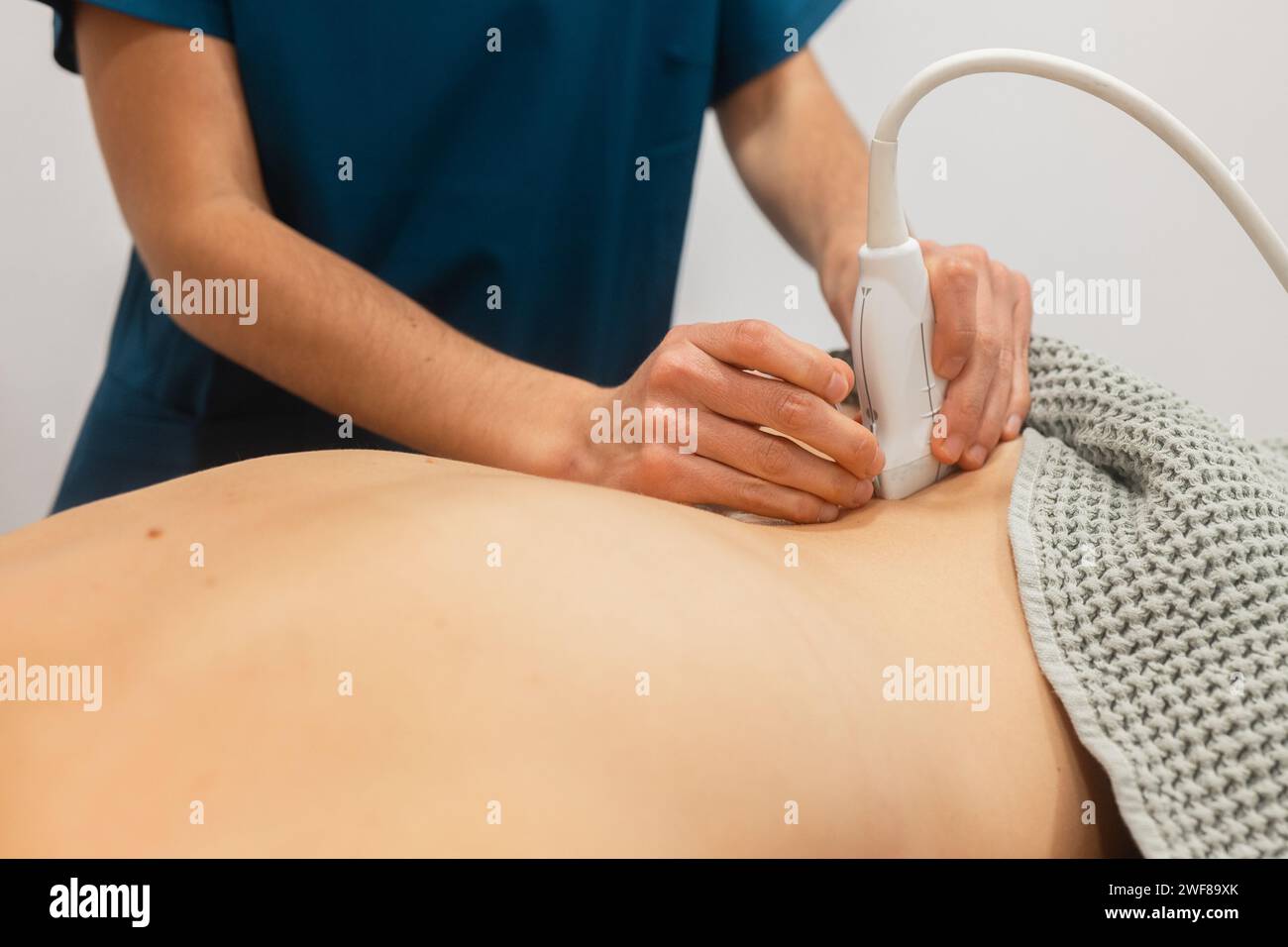 Un fisioterapista esegue la terapia a ultrasuoni sulla schiena del paziente, utilizzando un trasduttore sulla pelle Foto Stock