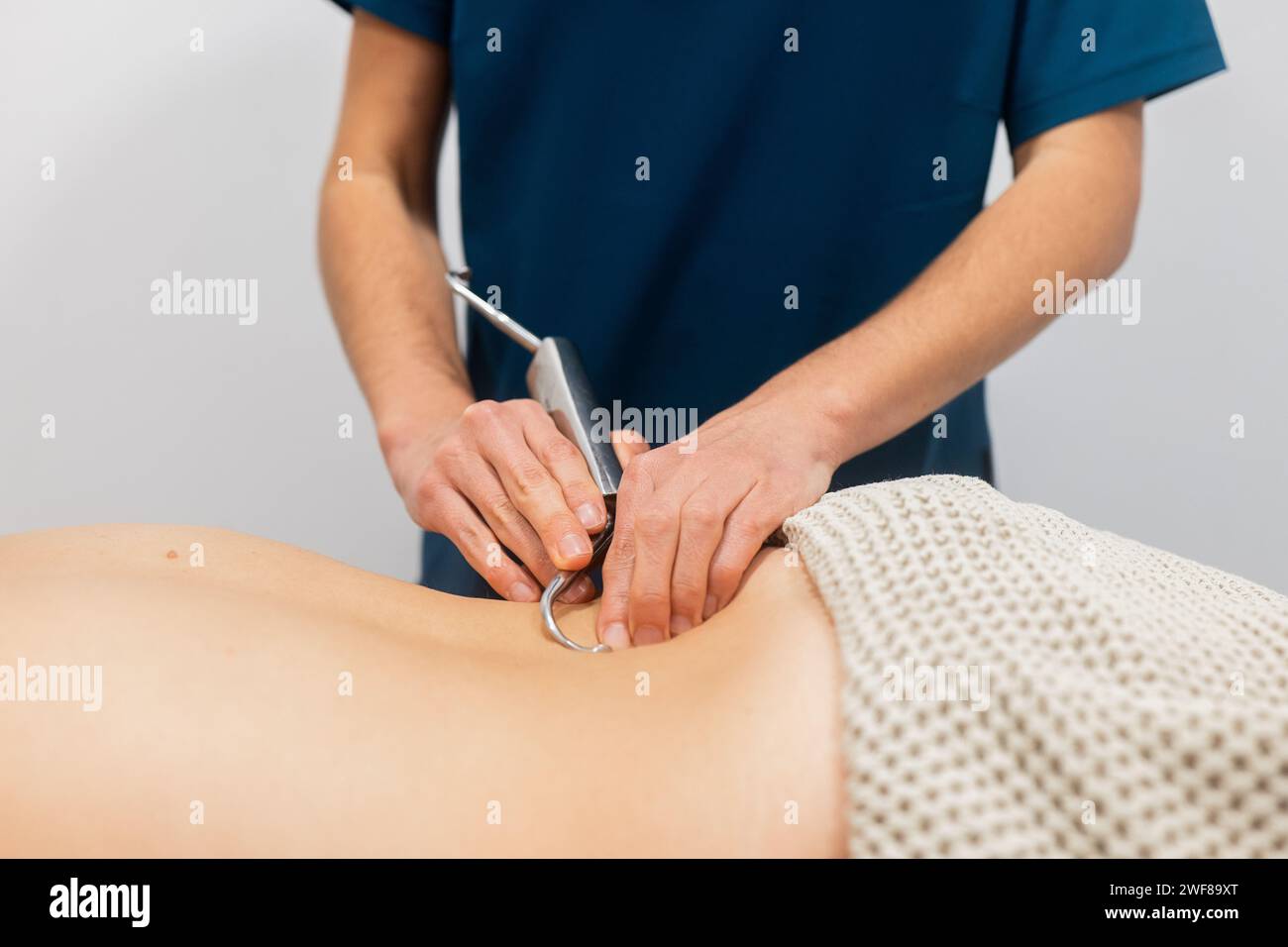 Un medico viene mostrato utilizzando una sonda ecografica sulla schiena del paziente, dimostrando le tecniche di terapia fisica Foto Stock