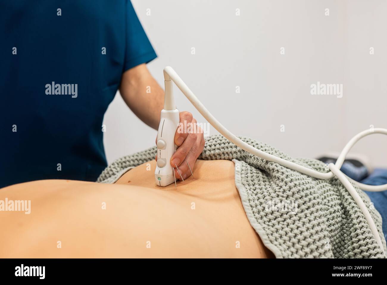 Un operatore sanitario esegue un'ecografia sull'area addominale del paziente, utilizzando un trasduttore per eseguire la scansione sulla pelle Foto Stock