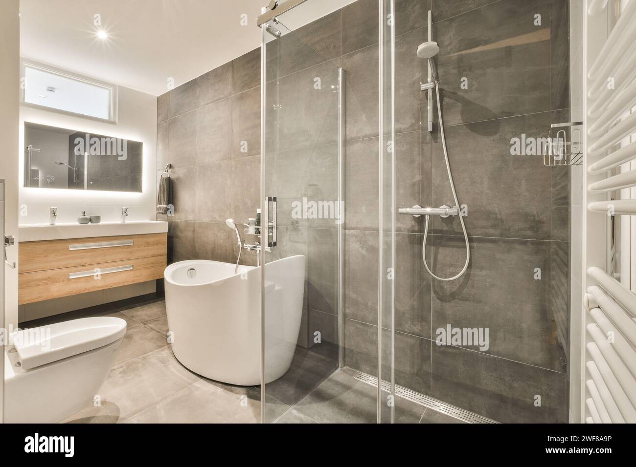 Bagno elegante e contemporaneo con cabina doccia, lavello a parete e design minimalista. Foto Stock