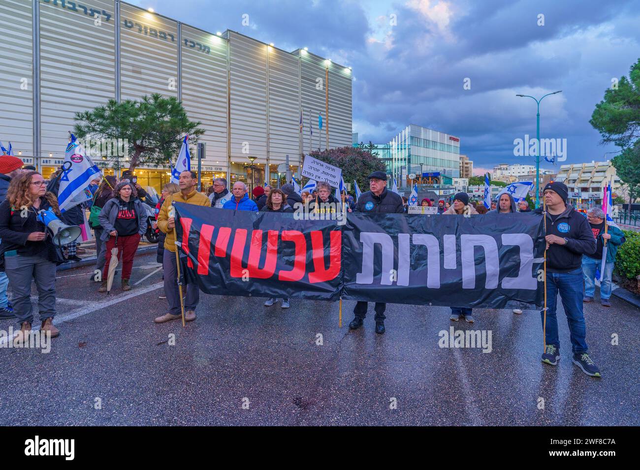 Haifa, Israele - 27 gennaio 2024: La gente marcia con vari segni e bandiere per protestare contro il governo, chiedendo nuove elezioni. Haifa, Israe Foto Stock