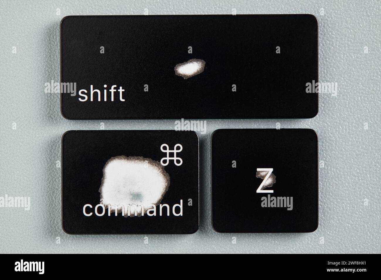Il tasto di comando, il tasto MAIUSC e il tasto Z sono usurati a causa dell'uso frequente e vengono rimossi da una tastiera con sfondo grigio Foto Stock