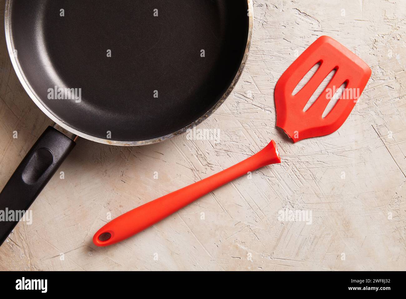 Spatola rossa rotta con padella su sfondo ruvido Foto Stock