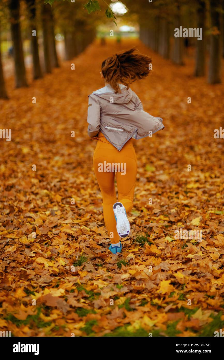 Ciao autunno. Vista da dietro donna in abiti da fitness nel parco, jogging. Foto Stock